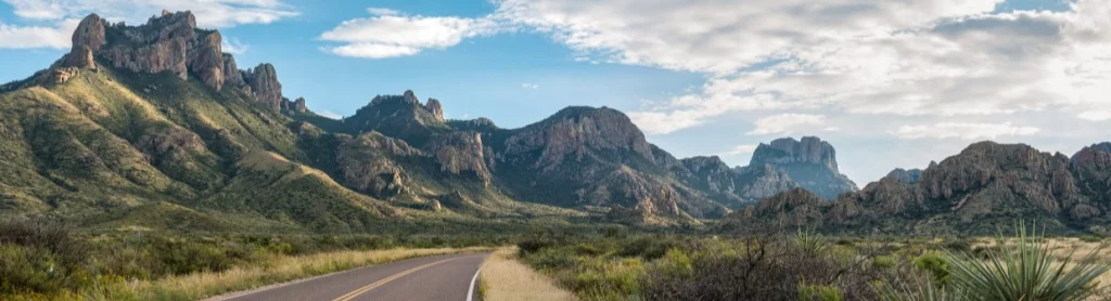 Lege tweebaansweg voert door een dal omringd door de kartelige pieken van de Chisos Mountains in Big Bend National Park