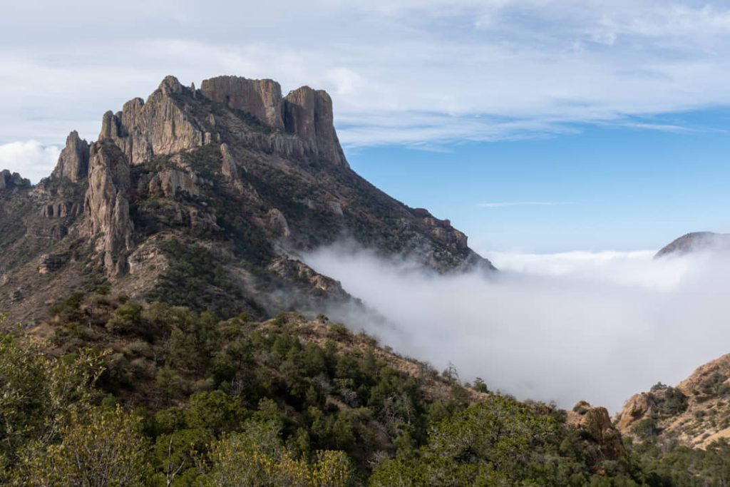 Ruige rotspiek van de Chisos Mountains steekt boven een dikke laag ochtendmist en wolken uit in Big Bend National Park