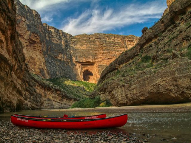 Rode kano op de rotsachtige oever van een rivier, met de hoge rotswanden van Santa Elena Canyon in Big Bend