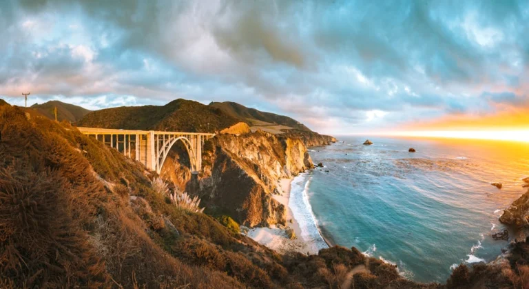 Iconische boogbrug Bixby Bridge over een kloof aan de kust van Big Sur, met een gouden zonsondergang boven de oceaan