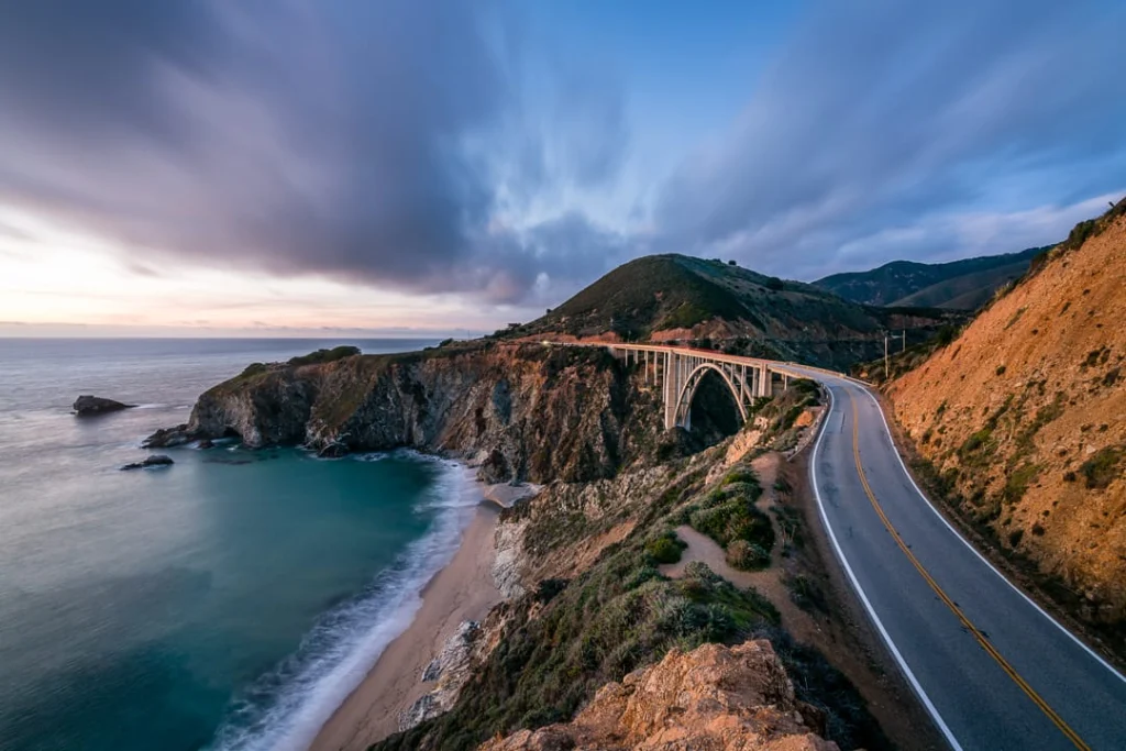 Gebogen brug over een kloof met uitzicht op een baai en de oceaan langs de kustweg van Big Sur