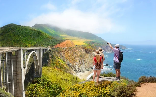 Stel kijkt vanaf een uitkijkpunt naar de gewelfde Bixby Bridge en de kust van Big Sur in de mist