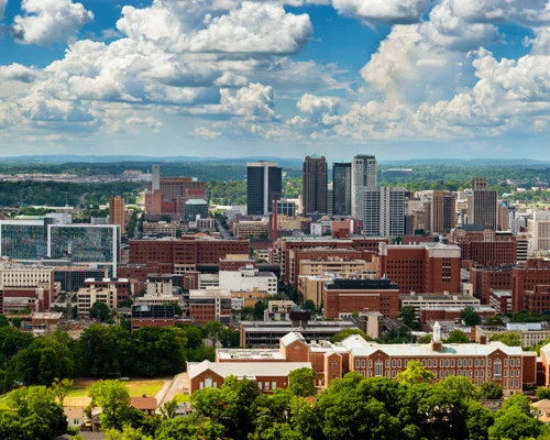 Luchtopname van het centrum van Birmingham in Alabama met kantoortorens tussen groen omringd door een dramatische wolkenlucht
