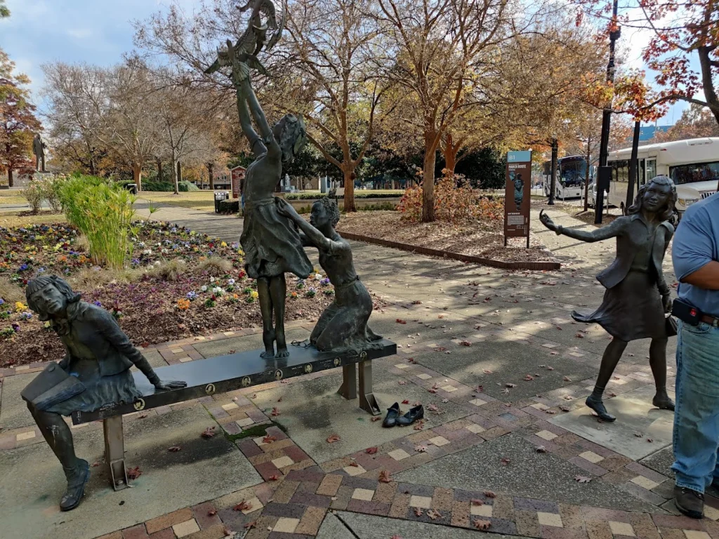 Bronzen standbeelden van kinderen die spelen bij een bankje in een herfstig park in Birmingham