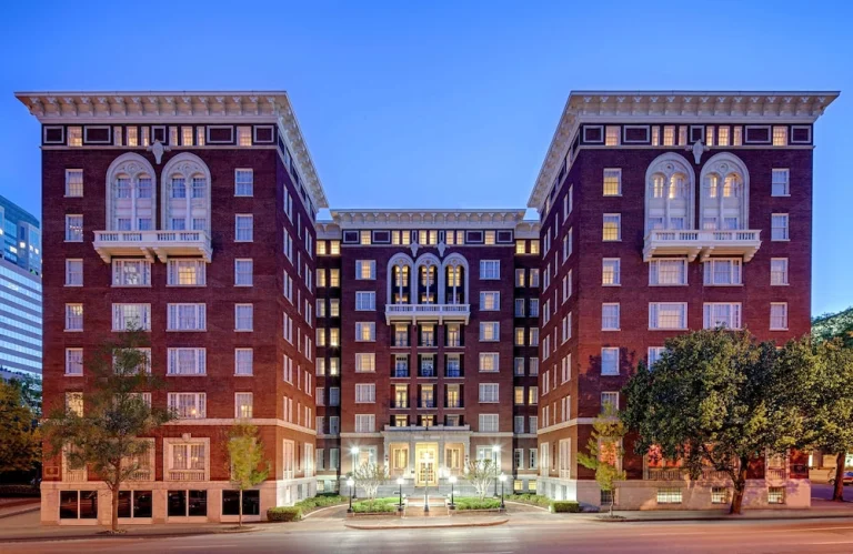 Een historisch bakstenen hotelgebouw met verlichte ramen en een ingang met trap fotografeerd tijdens de schemering in Birmingham
