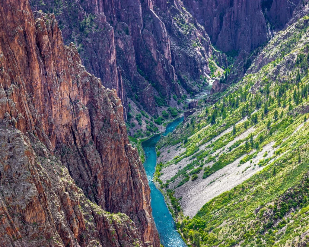 Smalle turquoise rivier kronkelt tussen steile donkere rotswanden op de bodem van de Black Canyon of the Gunnison in Colorado