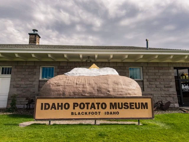 Gevel van het Idaho Potato Museum in Blackfoot met een groot beeld van een aardappel en een bord met de naam van het museum op het gazon