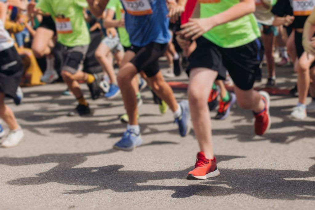 Close-up van de benen en sportschoenen van een groep hardlopers in fel gekleurde kleding tijdens een straatwedstrijd in Boston