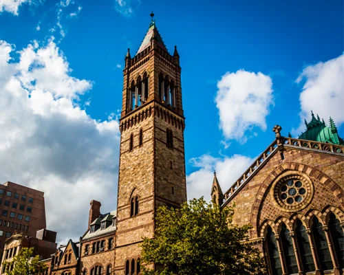 Detailopname van de bakstenen kerktoren met spits en glas in lood ramen naast een kerk met groen koperen dak in Boston