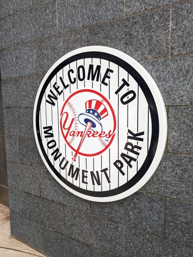 Rond bordje met het Yankees logo en de tekst Welcome to Monument Park tegen een stenen muur in Yankee Stadium
