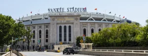 Stenen gevel met de tekst Yankee Stadium en vlaggenmasten boven de hoofdingang met verkeer op de brug ervoor
