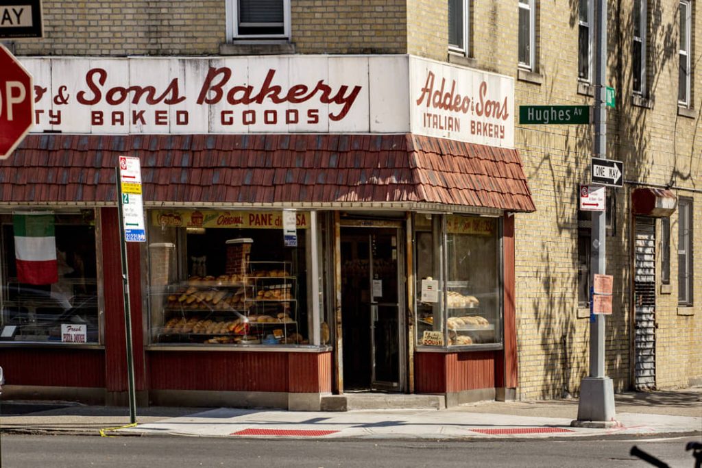 Winkelpui van een Italiaanse bakkerij met brood en gebak in de etalage en een rood dakluifel in de Bronx