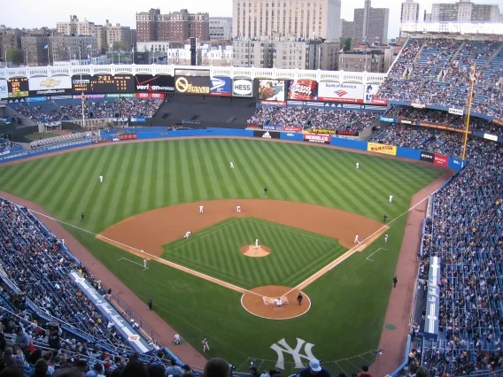 Overzicht vanaf hoog in de tribune over het groene honkbalveld en de volle tribunes van Yankee Stadium tijdens een wedstrijd
