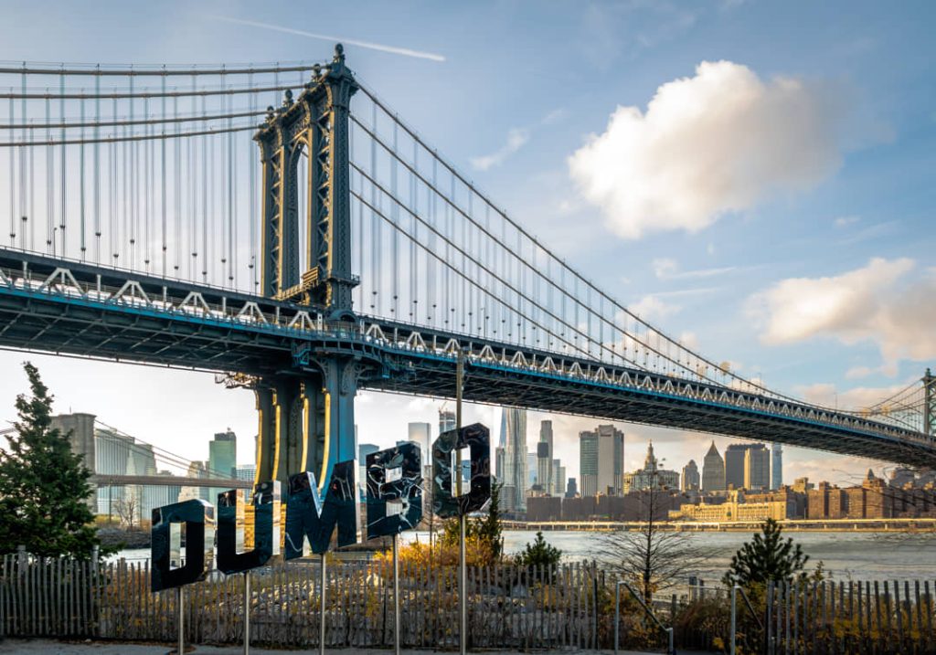 Groot bord met het opschrift Dumbo voor de Manhattan Bridge, met de skyline van Manhattan op de achtergrond in Brooklyn