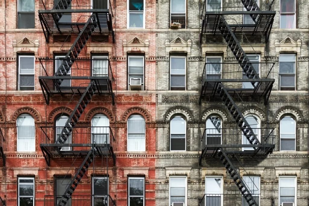 Symmetrische bakstenen gevel van een appartementengebouw in Brooklyn met zwarte brandtrappen en boogvormige ramen