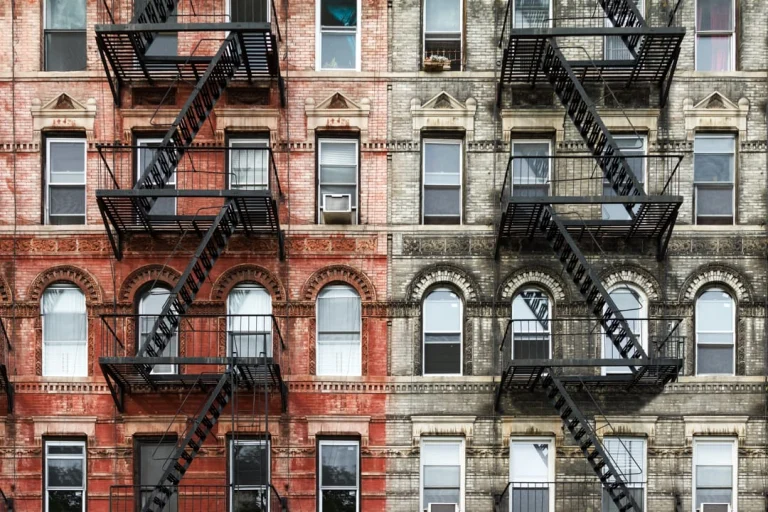 Symmetrische bakstenen gevel van een appartementengebouw in Brooklyn met zwarte brandtrappen en boogvormige ramen