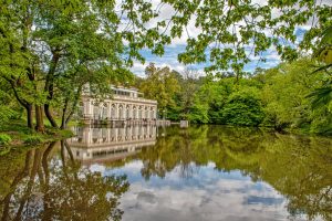 Wit classicistisch gebouw met zuilengalerij aan een rustige vijver, omringd door groene bomen in Prospect Park in Brooklyn