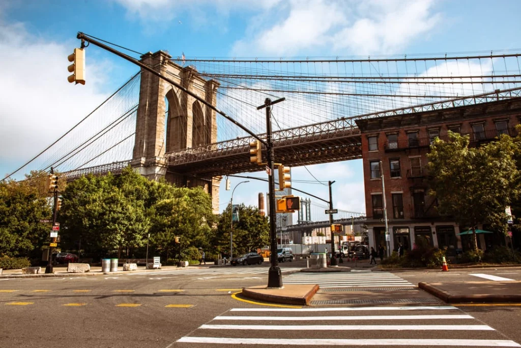 Verkeerslicht en zebrapad op een straathoek in Brooklyn met op de achtergrond de pijler en kabels van de Brooklyn Bridge