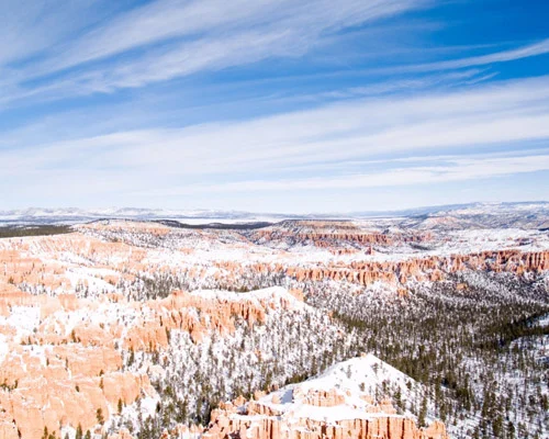 Uitgestrekt uitzicht over het met sneeuw bedekte amfitheater van Bryce Canyon National Park met bergen aan de horizon