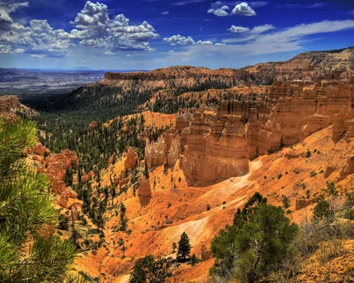 Duizenden oranje en witte rotspilaren vullen het amfitheater van Bryce Canyon National Park onder een blauwe hemel met stapelwolken