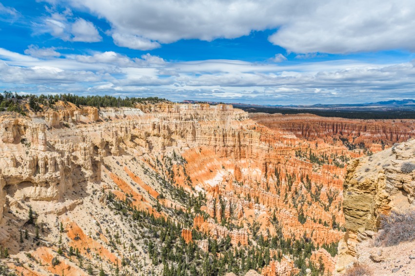 Panoramisch uitzicht over de oranje rotsformaties en hoodoos van Bryce Canyon National Park onder een blauwe lucht met wolken