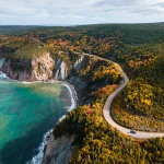 Kustweg de Cabot Trail slingert tussen kliffen en bos in herfstkleuren langs turquoise water op Cape Breton