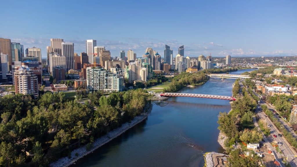 Luchtfoto van de skyline van Calgary met wolkenkrabbers, groene parken en de Bow River met een opvallende voetgangersbrug