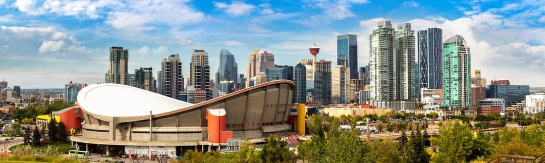 Panoramisch uitzicht op de skyline van Calgary met moderne wolkenkrabbers en de opvallende ronde Saddledome arena op de voorgrond