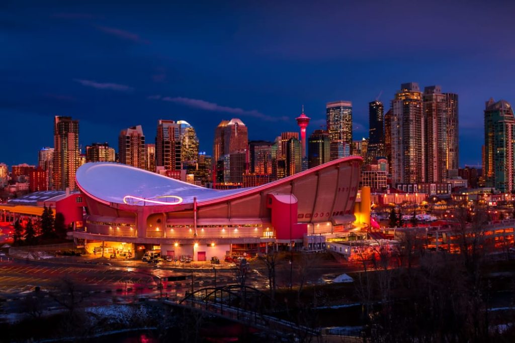 De skyline van Calgary met de Saddledome en verlichte wolkenkrabbers tijdens de schemering