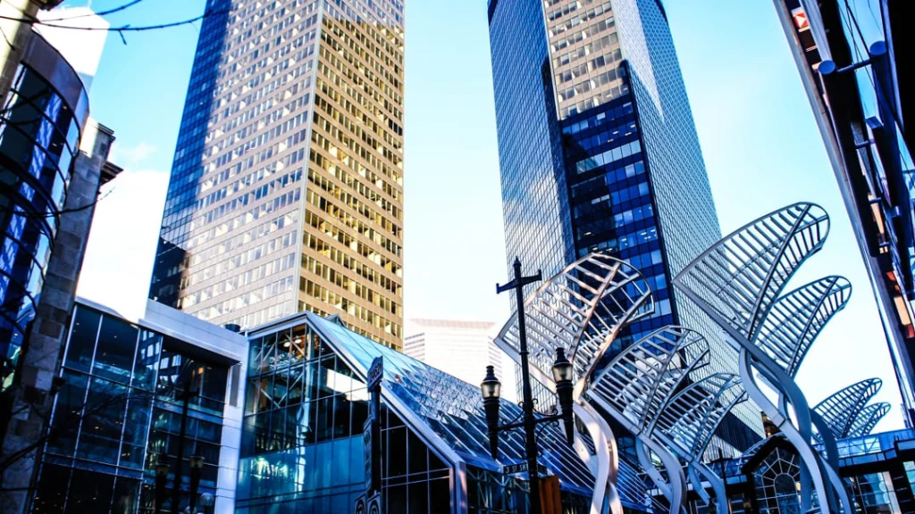 Moderne glazen wolkenkrabbers met een golvende metalen sculptuur op de voorgrond in het centrum van Calgary