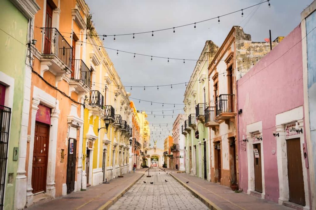 Een lege straat met pastelkleurige koloniale gevels en balkons, met lichtjes gespannen tussen de gebouwen in Campeche
