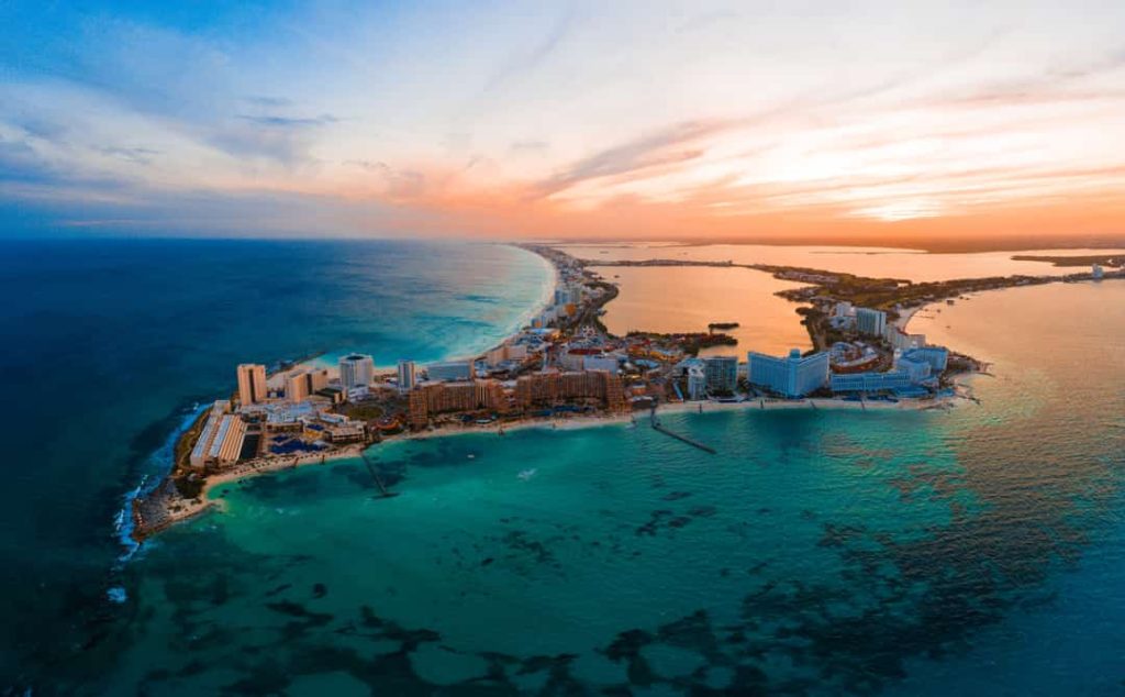 Luchtfoto van het smalle schiereiland met hotels van Cancún tussen de lagune en de zee bij een gouden zonsondergang