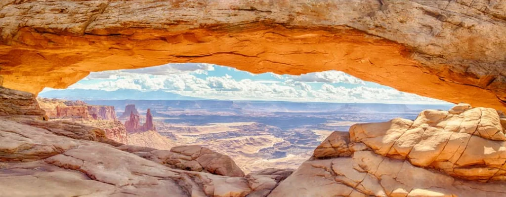 Beroemde rotsboog Mesa Arch met uitzicht op een uitgestrekt canyonlandschap, verlicht door de opkomende zon