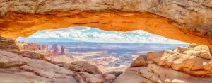 Beroemde rotsboog Mesa Arch met uitzicht op een uitgestrekt canyonlandschap, verlicht door de opkomende zon
