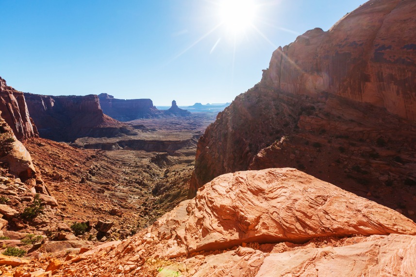 Uitzicht over een diepe, gelaagde canyon met rode en witte rotsformaties die zich uitstrekt tot aan de horizon