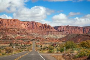 Lege tweebaansweg loopt recht op de gelaagde rode en witte rotswanden van Capitol Reef National Park af