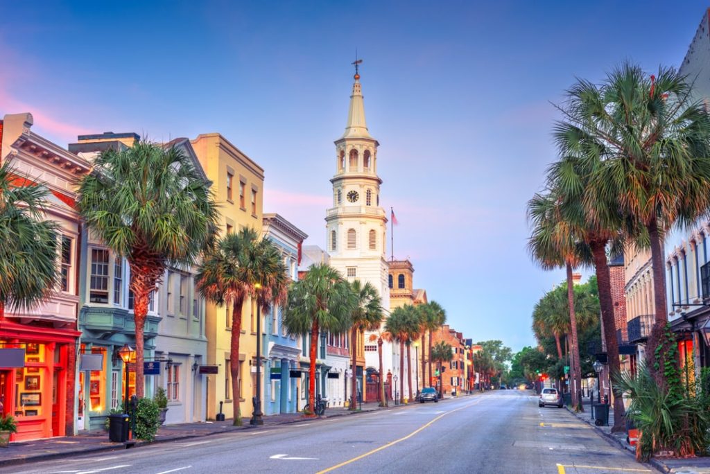Historische straat met kleurrijke gevels, palmbomen en een hoge witte kerktoren op de achtergrond in Charleston in South Carolina bij schemer