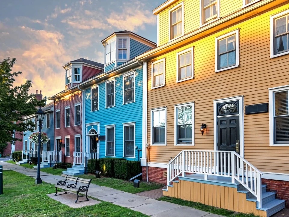 Rij houten huizen in rood, blauw en geel met witte trappen en een bankje op de stoep in het historische centrum van Charlottetown