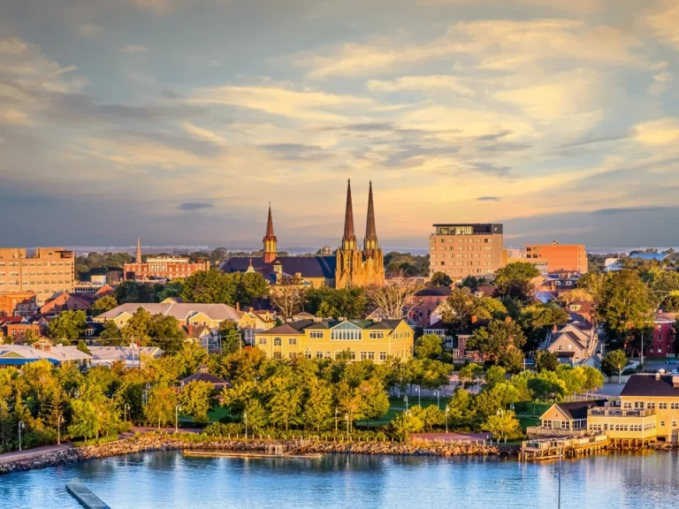 Uitzicht over de daken van Charlottetown met de torenspitsen van een kathedraal en gebouwen langs het water bij een gouden avondlucht