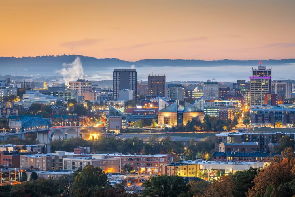 Verlichte skyline van Chattanooga bij schemering, met opstijgende mist en een rivier op de voorgrond