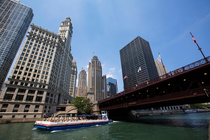 Rondvaartboot passeert de rivierbrug bij het Wrigley Building en de Tribune Tower onder een strakblauwe hemel in het centrum van Chicago