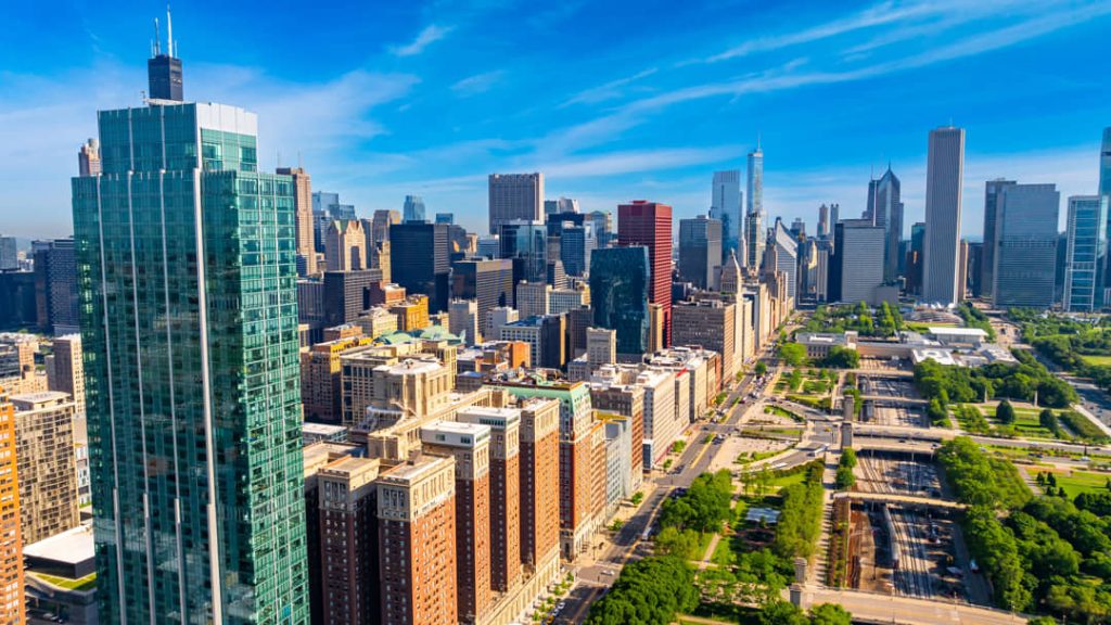 Luchtfoto bij zonsopgang van de wolkenkrabbers van Chicago met de Willis Tower op de achtergrond en een groen park met treinsporen op de voorgrond