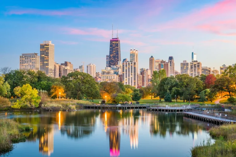 Wolkenkrabbers van Chicago weerspiegeld in het water van een vijver in Lincoln Park onder een roze en blauwe avondlucht