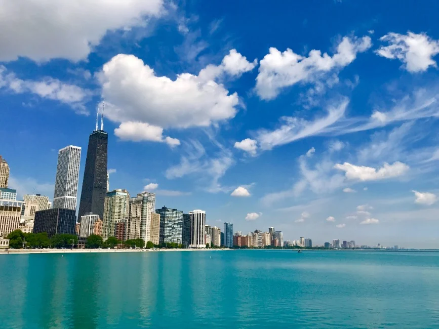 Wolkenkrabbers van Chicago inclusief de John Hancock-toren gezien over het turquoise water van het meer onder een blauwe lucht