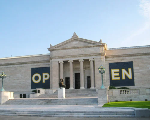 Neoclassicistisch museumgebouw met zuilen en een standbeeld, met twee grote banieren met de tekst OPEN op de gevel