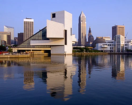 Glazen piramidevormig gebouw van het Rock and Roll Hall of Fame met de skyline van Cleveland weerspiegeld in het water