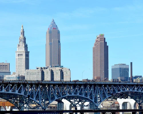 Wolkenkrabbers van Cleveland waaronder de Terminal Tower onder een blauwe lucht, met een stalen vakwerkbrug op de voorgrond
