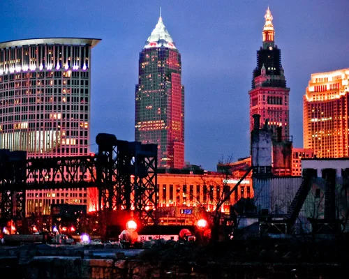 Verlichte wolkenkrabbers van Cleveland waaronder de Terminal Tower en Key Tower tegen een donkerblauwe avondlucht