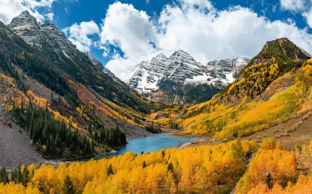 Besneeuwde bergtoppen van de Maroon Bells bij Aspen in Colorado met een helderblauw meer en goudgele espenbomen in de vallei