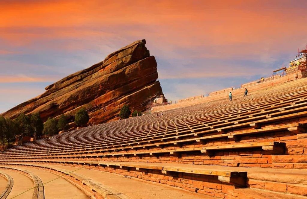 De rode rotsformaties en trapsgewijze zitplaatsen van het Red Rocks amfitheater in Colorado kleuren oranje bij zonsondergang